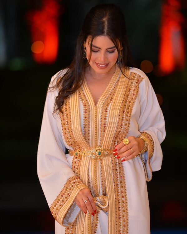 CAFTAN EXPORT Découvrez l'élégance intemporelle du caftan henna, une pièce traditionnelle marocaine magnifiquement ornée. Nos caftans en henna allient beauté et tradition pour des moments inoubliables. Explorez notre collection unique aujourd'hui ! Le caftan Umnia se compose de deux pièces en velours de soie violet foncé, ornées de broderies dorées, violet, turquoise. de perles en cristal, de sfifa et de boutons en skali doré. La partie inférieure est confectionnée en drap de turquoise, perlé à la main. Il est accompagné d'une ceinture assortie en sekali.