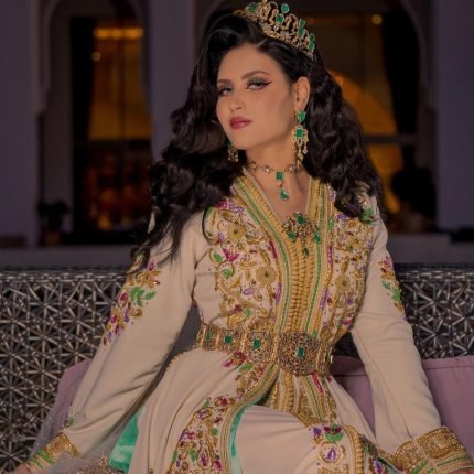 CAFTAN EXPORT Découvrez l'élégance intemporelle du caftan henna, une pièce traditionnelle marocaine magnifiquement ornée. Nos caftans en henna allient beauté et tradition pour des moments inoubliables. Explorez notre collection unique aujourd'hui ! Caftan effet deux pièces en drap de soie beige, orné de broderies en fil bronze et de perles faites à la main. La jupe est attachée au caftan au niveau de la taille, également ornée de broderies et de perles. Le caftan peut être porté sans la jupe et est livré avec une ceinture assortie en métal bronze.