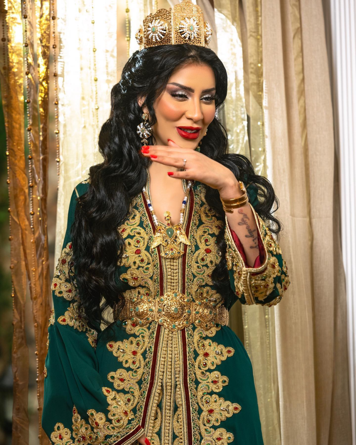 CAFTAN EXPORT Découvrez l'élégance intemporelle du caftan henna, une pièce traditionnelle marocaine magnifiquement ornée. Nos caftans en henna allient beauté et tradition pour des moments inoubliables. Explorez notre collection unique aujourd'hui ! Le caftan se compose de deux pièces en crêpe de soie vert, ornées de broderies dorées, de perles en cristal, de sfifa et de boutons en skali doré. La partie inférieure est confectionnée en drap de soie vert, perlé à la main. Il est accompagné d'une ceinture assortie en métal.