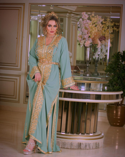 CAFTAN EXPORT Découvrez l'élégance intemporelle du caftan henna, une pièce traditionnelle marocaine magnifiquement ornée. Nos caftans en henna allient beauté et tradition pour des moments inoubliables. Explorez notre collection unique aujourd'hui ! Le caftan Amira, composé de deux pièces en crêpe de soie, est travaillé avec broderie, sfifa et des boutons en skali doré. La partie inférieure est un caftan sans manche, confectionnée en drap de soie blanc. Il est accompagné d'une ceinture assortie en métal.